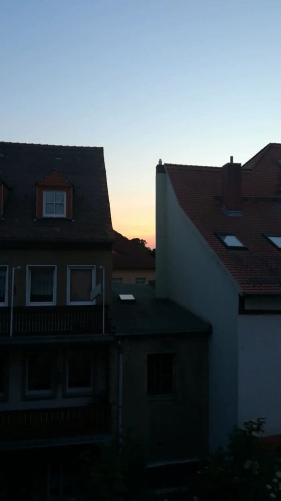 Ein Blick auf zwei Häuser - zwischen den Haushälften kann man den Sonnenuntergang sehen. 